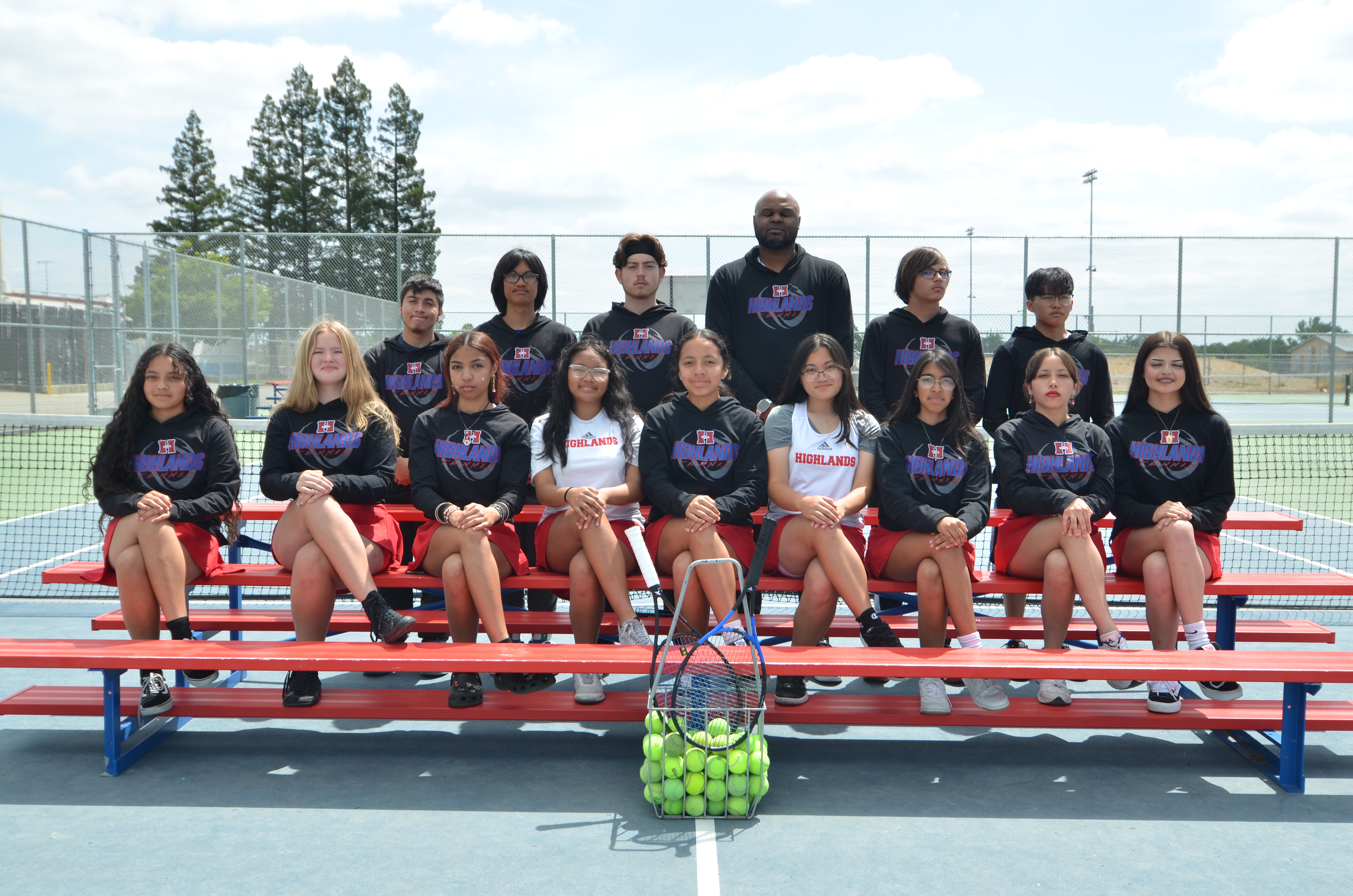 tennis team on benches in middle of tennis court